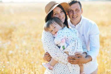 Mutlu bir çocukluk, aile buğday tarlasında yürüyor. Anne, baba ve küçük kız birlikte dışarıda vakit geçiriyorlar. Ebeveynler ve çocuklar yaz otlaklarında oynuyorlar. Yüksek kalite fotoğraf