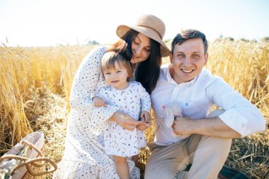 Mutlu bir çocukluk, aile buğday tarlasında yürüyor. Anne, baba ve küçük kız birlikte dışarıda vakit geçiriyorlar. Ebeveynler ve çocuklar yaz otlaklarında oynuyorlar. Yüksek kalite fotoğraf