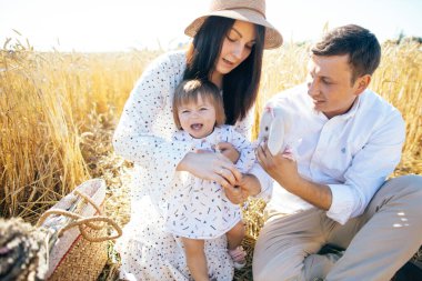 Mutlu bir çocukluk, aile buğday tarlasında yürüyor. Anne, baba ve küçük kız birlikte dışarıda vakit geçiriyorlar. Ebeveynler ve çocuklar yaz otlaklarında oynuyorlar. Yüksek kalite fotoğraf