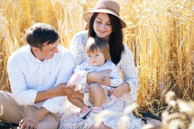Mutlu bir çocukluk, aile buğday tarlasında yürüyor. Anne, baba ve küçük kız birlikte dışarıda vakit geçiriyorlar. Ebeveynler ve çocuklar yaz otlaklarında oynuyorlar. Yüksek kalite fotoğraf