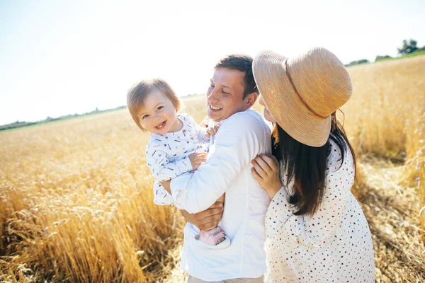 Mutlu bir yaz yürüyüşü yapan aile, anne, baba ve çocuk buğday tarlasında yürüyor ve gün batımında güzel doğanın tadını çıkarıyor. Yüksek kalite fotoğraf