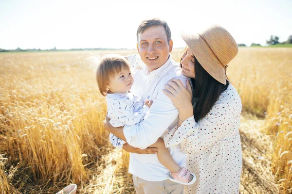 Mutlu bir çocukluk, aile buğday tarlasında yürüyor. Anne, baba ve küçük kız birlikte dışarıda vakit geçiriyorlar. Ebeveynler ve çocuklar yaz otlaklarında oynuyorlar. Yüksek kalite fotoğraf