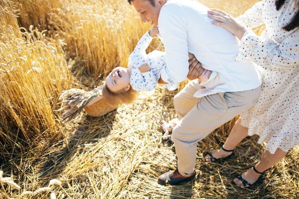 Happy family on a summer walk, mother, father and child walk in the wheat field and enjoy the beautiful nature, at sunset. High quality photo