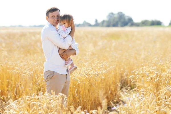 stock image young man with beautiful daughter walking in wheat field. father tenderly touches hir sons hair, holding hands, hugs. High quality photo