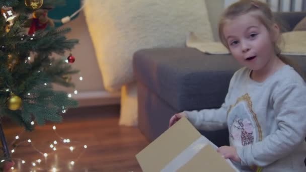 Spännande Nyfiken Liten Flicka Ler Öppnar Julklappar Vackert Inredda Julgran — Stockvideo