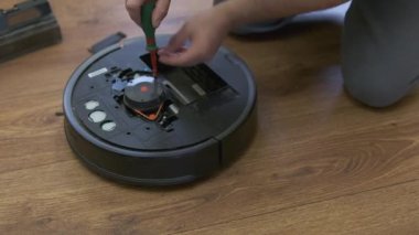 Kafkasyalı genç adam elektrikli süpürge robot bakımı yapıyor. Erkek otomatik elektrik süpürgesine başlar. Robot elektrik süpürgesi tamiri. Yüksek kalite fotoğraf