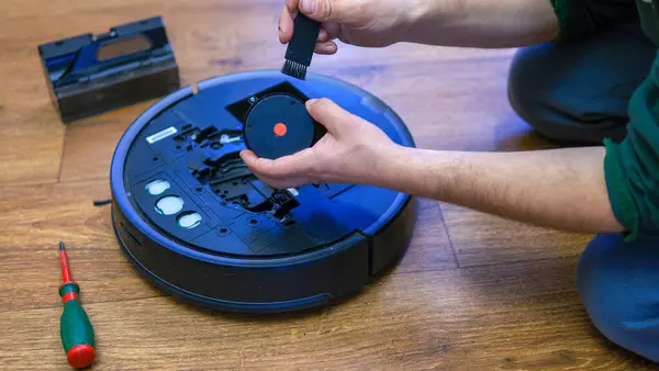 A man is fixing robot vacuum cleaner by hand holding screwdriver to open the cover. Consumables for a robot vacuum cleaner. High quality photo