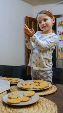 Küçük bir kız mutfak masasında zencefilli kurabiye süslüyor. Noel için hazırlanıyorum. Yüksek kalite fotoğraf