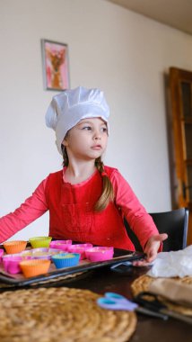 Küçük beyaz kız, aşçı şapkası takıyor, oyuncak mutfağında aşçılık oynuyor. Yüksek kalite fotoğraf