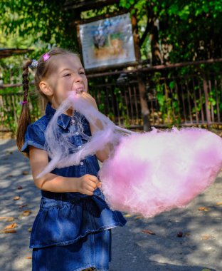 Yazın dışarıda pamuk helva yiyen sevimli küçük bir kız. Yüksek kaliteli FullHD görüntüler