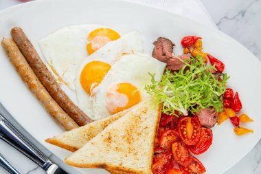 Çırpılmış yumurta, sebze, kiraz domates, ekmek, bitki ve sosis.