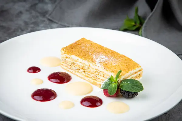 white sponge cake with drops of syrup, mint and wild berries