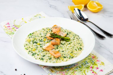 enginarlı pirinç lapası, beyaz tabakta kırmızı balık ve otlar.