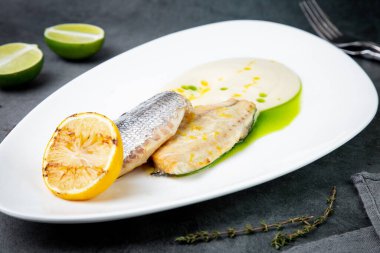 Soslu kızarmış balık parçaları ve beyaz tabakta kızarmış limon.