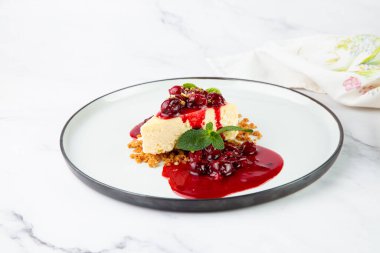 Meyveli cheesecake ve beyaz tabakta nane şekeri.