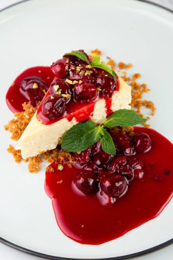 Meyveli cheesecake ve beyaz tabakta nane şekeri.