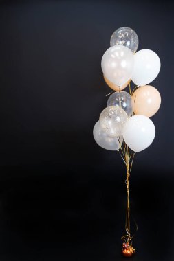 Siyah arka planda, beyaz, bej, şeffaf, açık tonlu balonlar uçuyor. Mesaj için yer var. Yüksek kalite fotoğraf