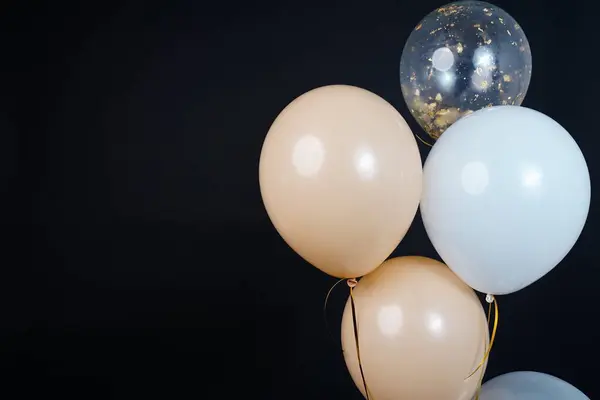 Bunch of balloons of white, beige and transparent colors on a dark background. Place for the inscription. High quality photo