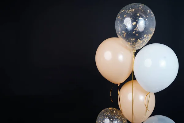 Bunch of balloons of white, beige and transparent colors on a dark background. Place for the inscription. High quality photo