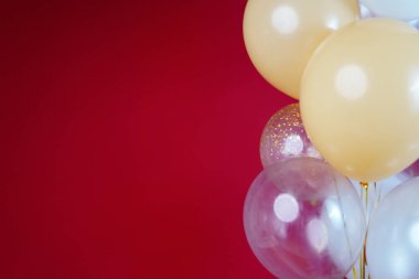 Açık renkli balonlar - beyaz, bej, şeffaf, kırmızı arkaplanda inci. Yatay fotoğraf. Mesaj için yer var. Yüksek kalite fotoğraf