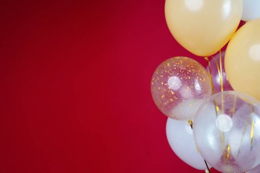 Açık renkli balonlar - beyaz, bej, şeffaf, kırmızı arkaplanda inci. Yatay fotoğraf. Mesaj için yer var. Yüksek kalite fotoğraf