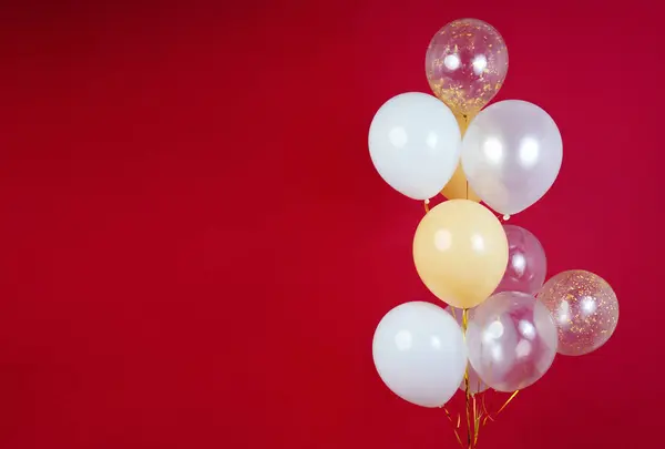 Light balloons - white, beige, transparent, pearl on a red background. Horizontal photo. Space for text. High quality photo