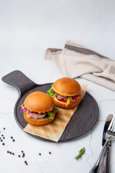 hot burgers with lettuce and vegetables on a wooden board