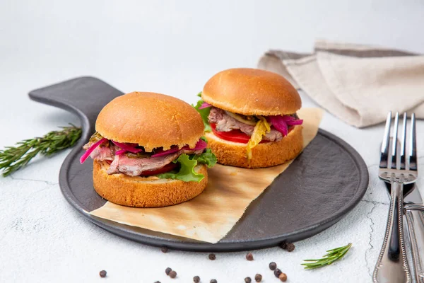 hot burgers with lettuce and vegetables on a wooden board