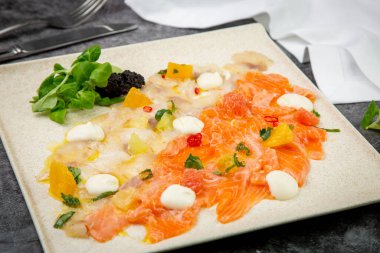 Mozzarella peyniri ve bitkilerle dilimlenmiş kırmızı ve beyaz balık.