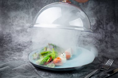 Farklı salata türleri marul ve balık ruloları bir bardak altında