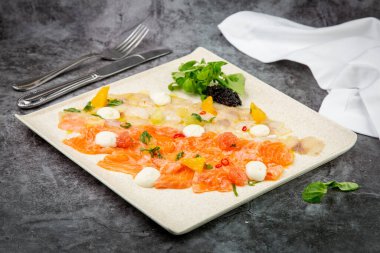 Mozzarella peyniri ve bitkilerle dilimlenmiş kırmızı ve beyaz balık.