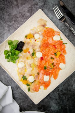 Mozzarella peyniri ve bitkilerle dilimlenmiş kırmızı ve beyaz balık.