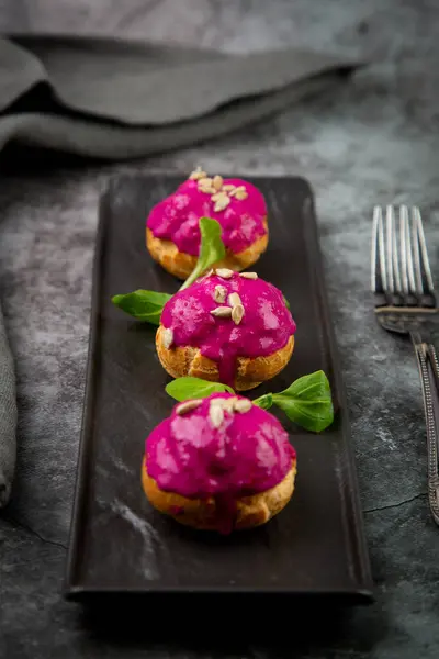 dessert of baked buns with raspberry topping and seed decorations