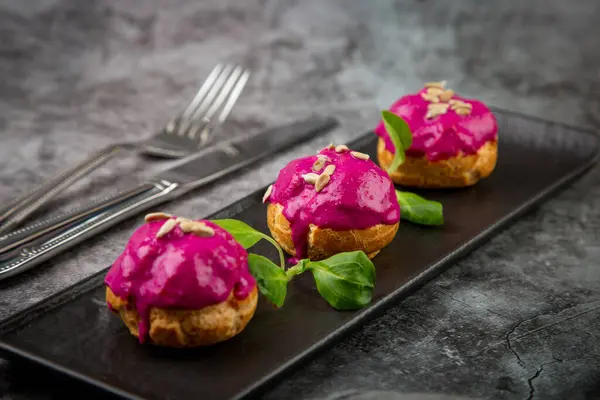 dessert of baked buns with raspberry topping and seed decorations