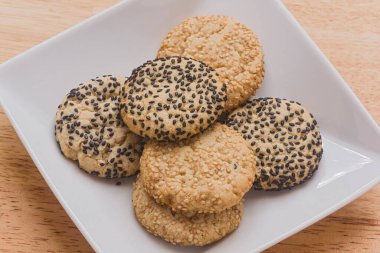 Close up of Sesame tea cakes on a white plate on a wooden coutertop.