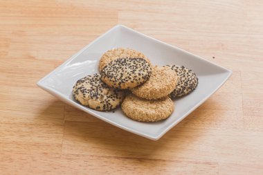 Sesame tea cakes on a white plate on a wooden coutertop.
