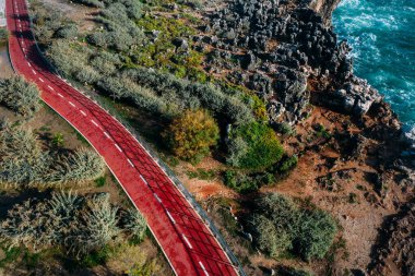 Hava aracı, güneşli bir günde Cascais, Portekiz sahillerini kucaklayan kırmızı bisiklet yolunu gösteriyor.