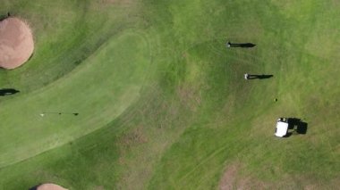 Güneşli bir günde Algarve, Portekiz 'deki bir golf sahasındaki tanımlanamayan golfçülerin yukarıdan görünüşü. Uzun öğleden sonra gölgeleri