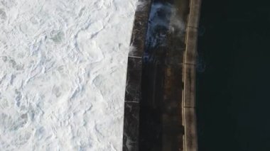 Okyanus dalgalarının yukarıdan aşağıya insansız hava aracı atışı deniz kıyısı savunmasına çarpıyor.