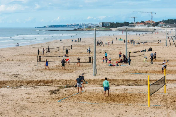 Lizbon, Portekiz - 17 Aralık 2022: Lizbon, Portekiz 'deki Carcavelos Sahili' nde plaj tenisi ve sörf yapan insanların yüksek perspektifli görüntüsü