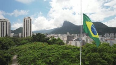 Approaching a Brazilian flag with background of Christ the Redeemer covered in clouds in Rio de Janeiro, Brazil