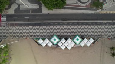 Top down aerial panning view of unidentifiable people walking on the famous Copacabana Beach sidewalk in Rio de Janeiro, Brazil at dusk