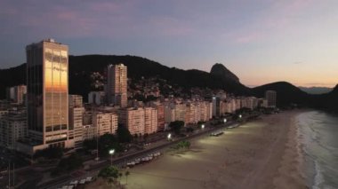 Aerial drone view over Leme Beach in the Copacabana District, Rio de Janeiro, Brazil at dusk. Sugarloaf mountain is barely visible in the background