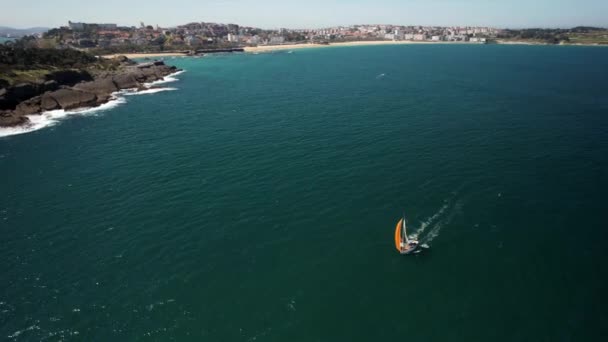 スペインのカンタブリア州サンタンデールのマグダレナ半島近くのオレンジ色の帆船の空中ドローン軌道 — ストック動画