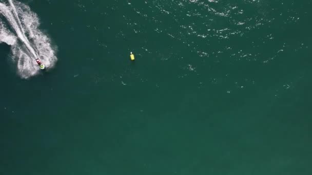 高速ジェットスキーヤーのトップダウン空中ドローンビューは ポルトガル アルガルヴェ ヴィラモウラで撮影された水の上に目覚めを残して曲線を作ります — ストック動画