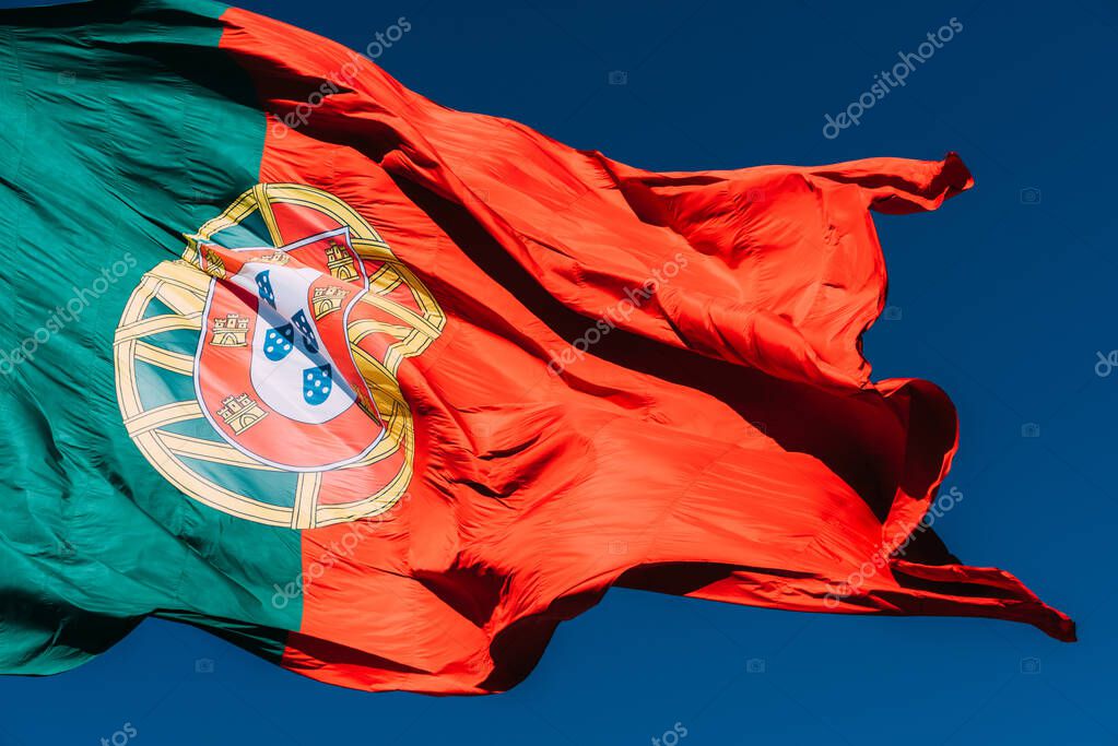 Portugal flag isolated on the blue sky waving in the wind.