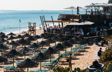 Algarve, Portekiz - 23 Haziran 2023: İnsanlar Portekiz 'in Algarve kentindeki Garrao Poente Plajı' ndaki plaj barında dinleniyor.
