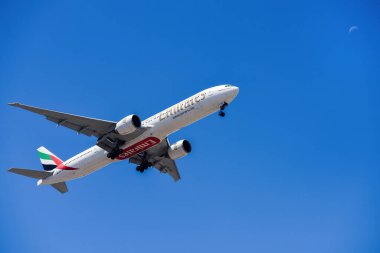 Lizbon, Portekiz - 12 Temmuz 2023: BAE merkezli havayolu şirketi Emirates ve Boeing 777-300ER Lizbon Uluslararası Havaalanı 'na iniş yapmak üzere mavi gökyüzüne doğru yaklaşıyorlar