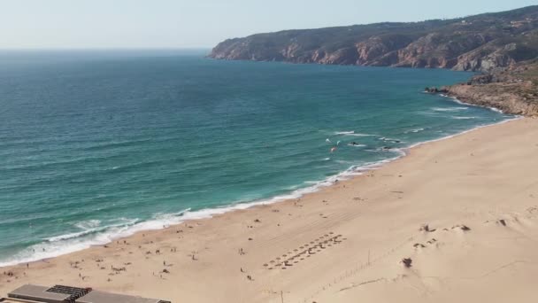 遠い背景に水とカボダロカのキテスサーファーとギンチョビーチの空中ドローン軌道ビュー — ストック動画