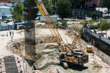 Lizbon, Portekiz - 31 Temmuz 2023: Temel atma, manuel işçiler, makineler, vinçler ve dökülen çimento - inşaat alanı konsepti de dahil olmak üzere yoğun bir inşaat alanının yüksek perspektifi